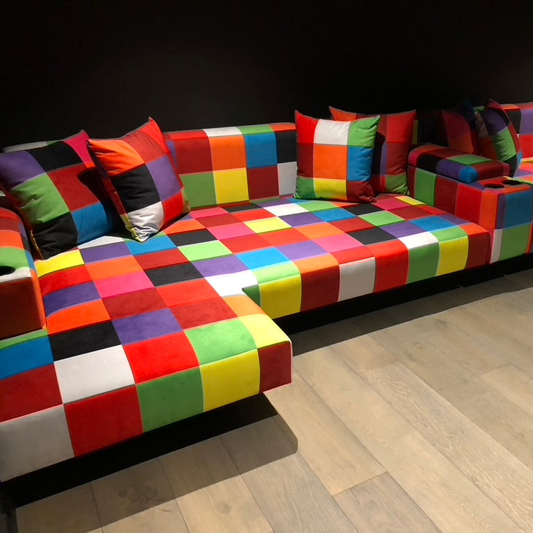 Multicolored checkered sofa with patterned cushions on a wooden floor.